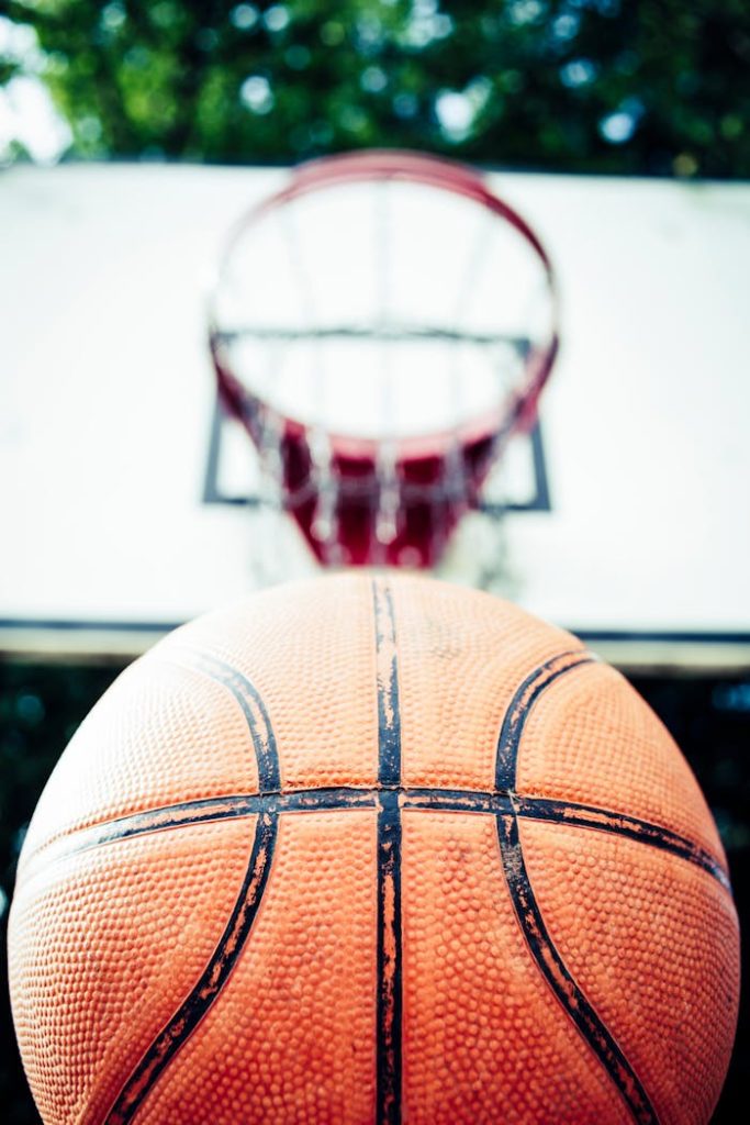 Vivid image of a basketball aiming for a hoop outdoors in daylight.